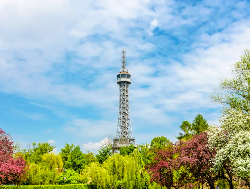 Petrin Tower in Prague surrounded by lush gardens and colorful trees.