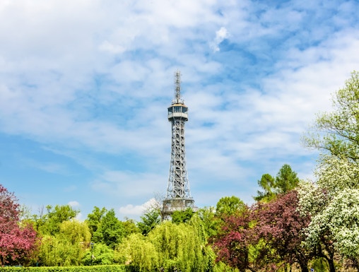 Petrin Tower in Prague surrounded by lush gardens and colorful trees.