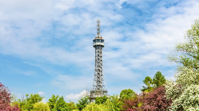 Petrin Tower in Prague surrounded by lush gardens and colorful trees.