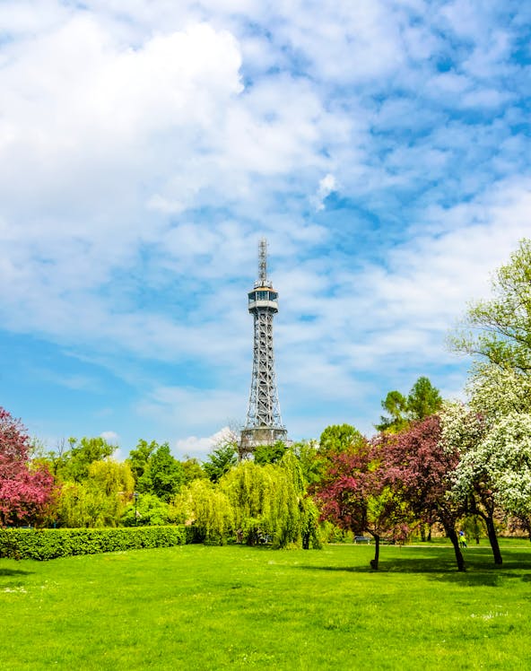 Petrin Tower in Prague surrounded by lush gardens and colorful trees.
