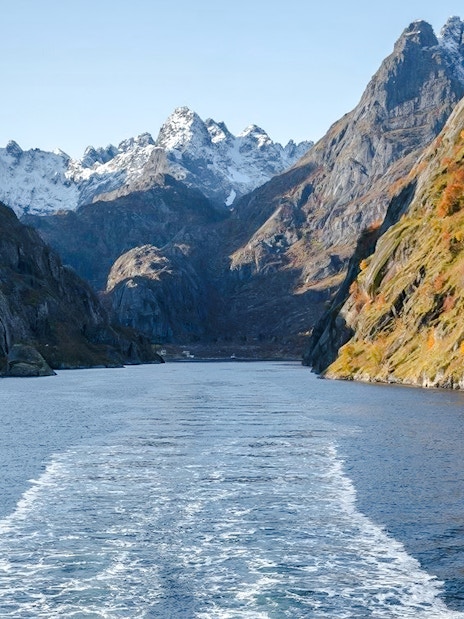 Cruise view of steep cliffs and snowy peaks in Silent Trollfjord, Lofoten.