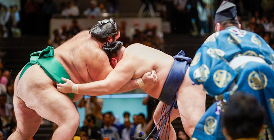 Sumo wrestlers competing in a traditional match at an Osaka tournament.