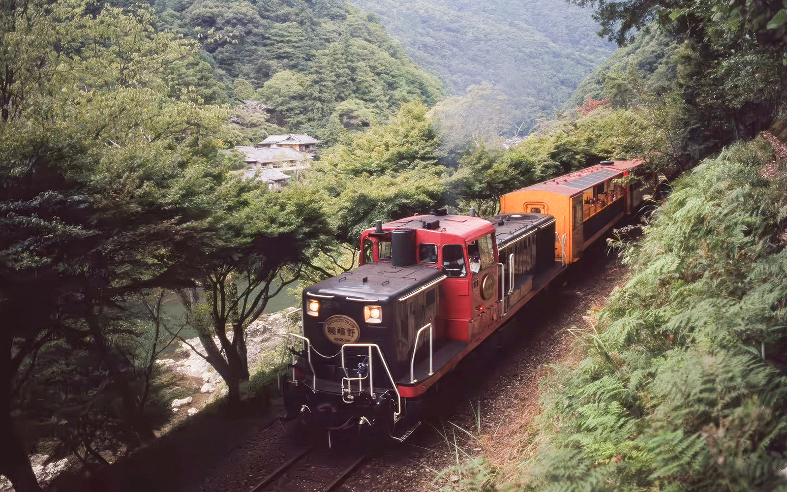 Sagano Romantic Train passing through lush greenery in Kyoto, Japan.