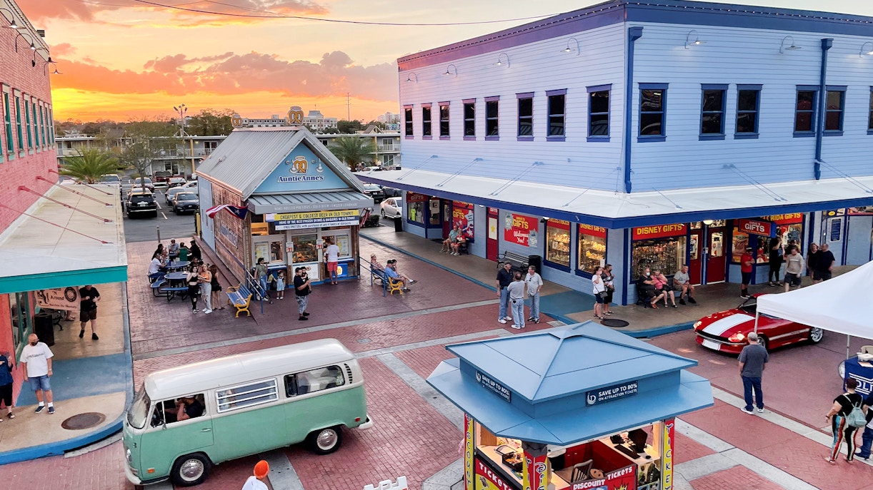 Old Town Orlando at sunset with shops, visitors, and a vintage van in the plaza.