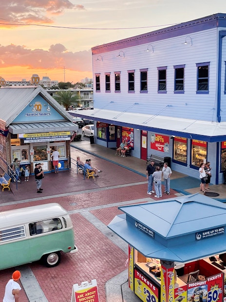 Old Town Orlando at sunset with shops, visitors, and a vintage van in the plaza.