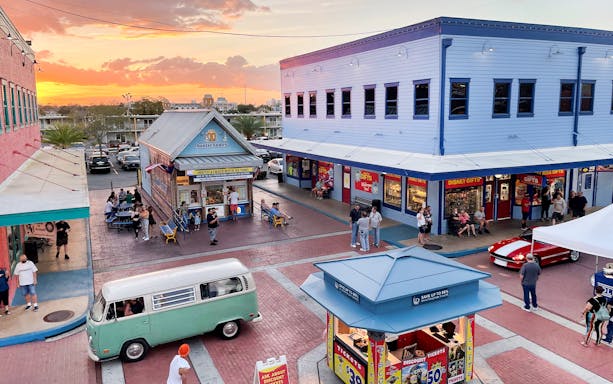 Old Town Orlando at sunset with shops, visitors, and a vintage van in the plaza.