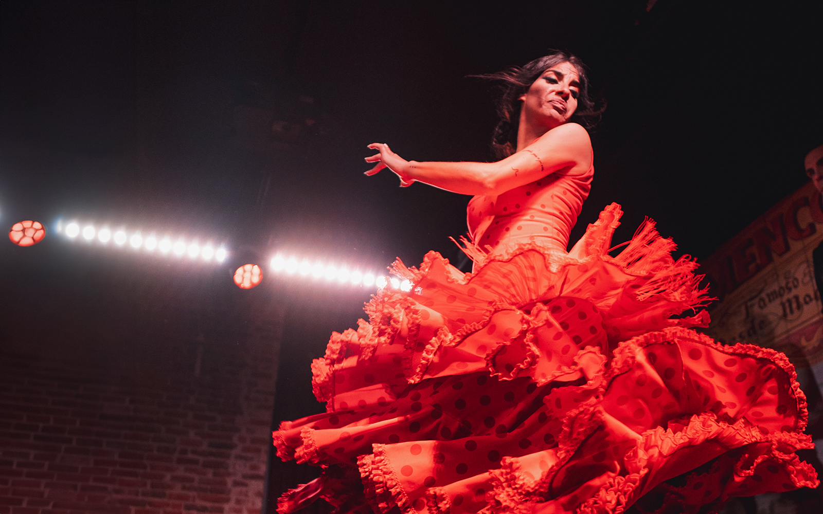 Flamenco dancer performing at Flamenco De Leones Show in vibrant red dress.