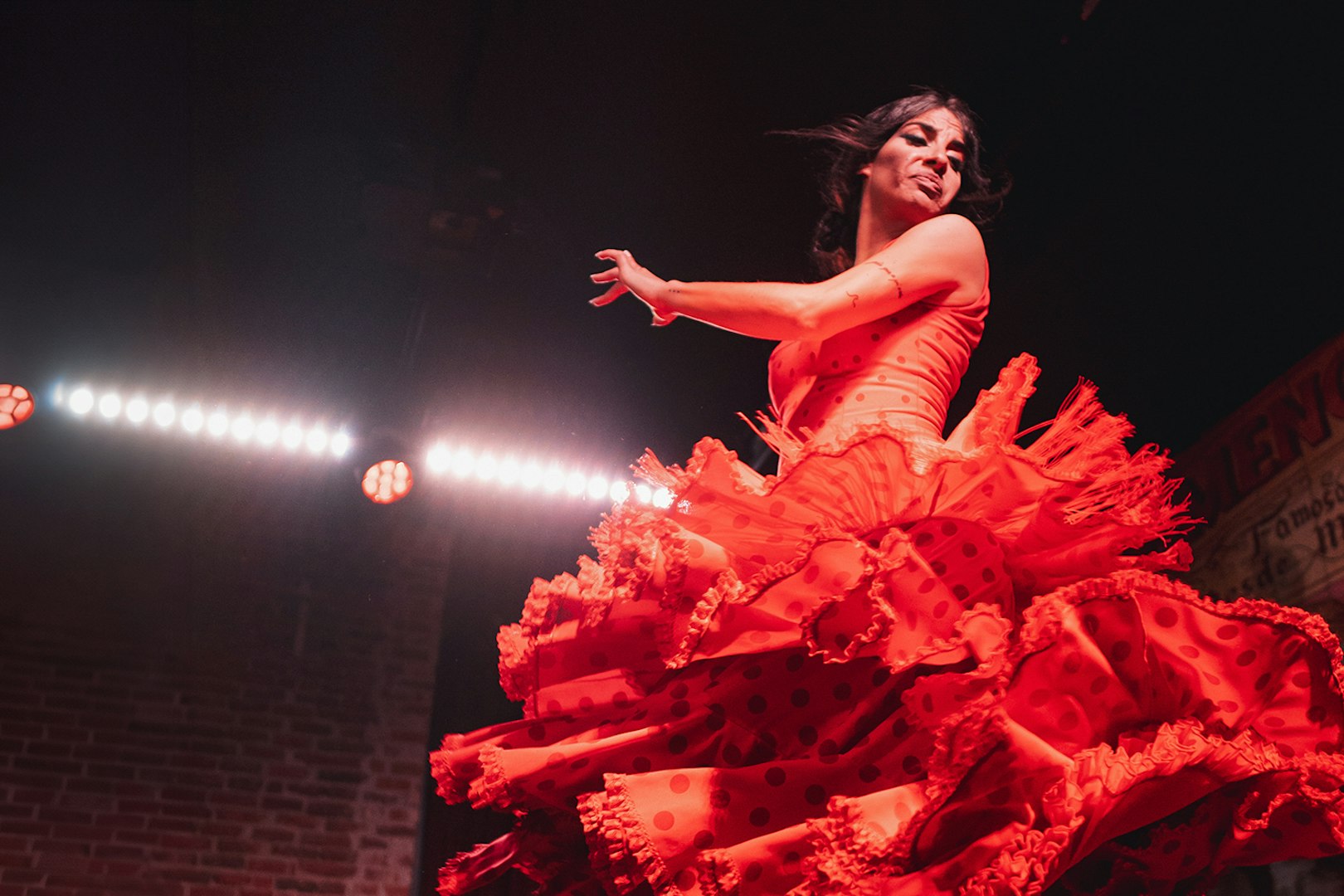 Flamenco dancer performing at Flamenco De Leones Show in vibrant red dress.