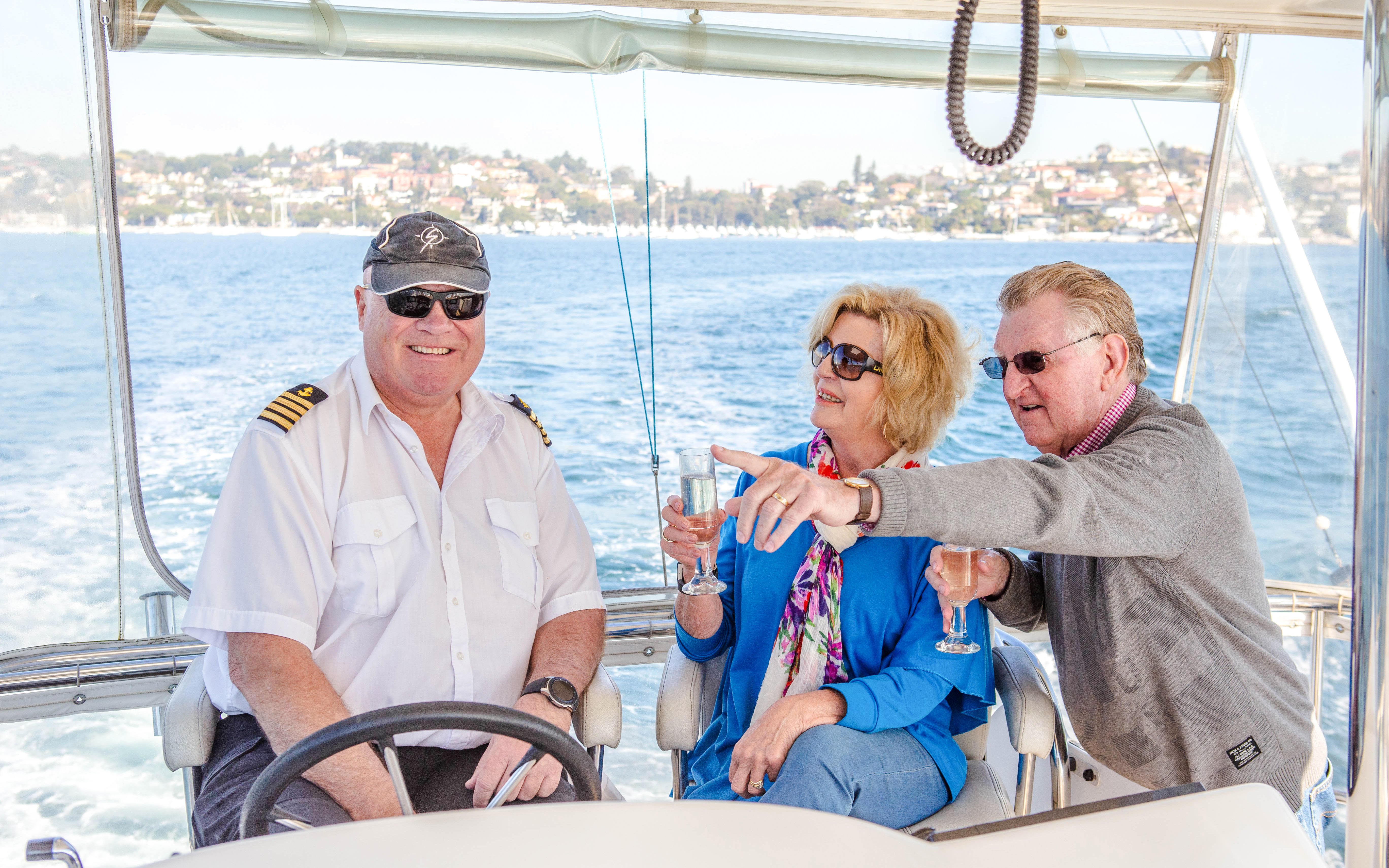 Captain and guests enjoying Sydney Harbour luxury lunch cruise with views of the shoreline.
