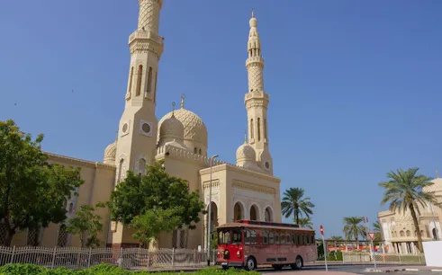 Red trolley in front of Jumeirah Mosque, part of Emirati Trolley Tour in Dubai.
