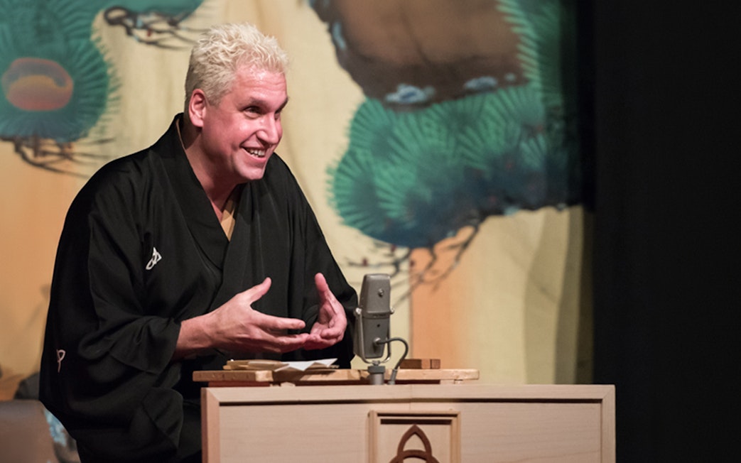 Performer in traditional attire delivering Rakugo storytelling on stage.