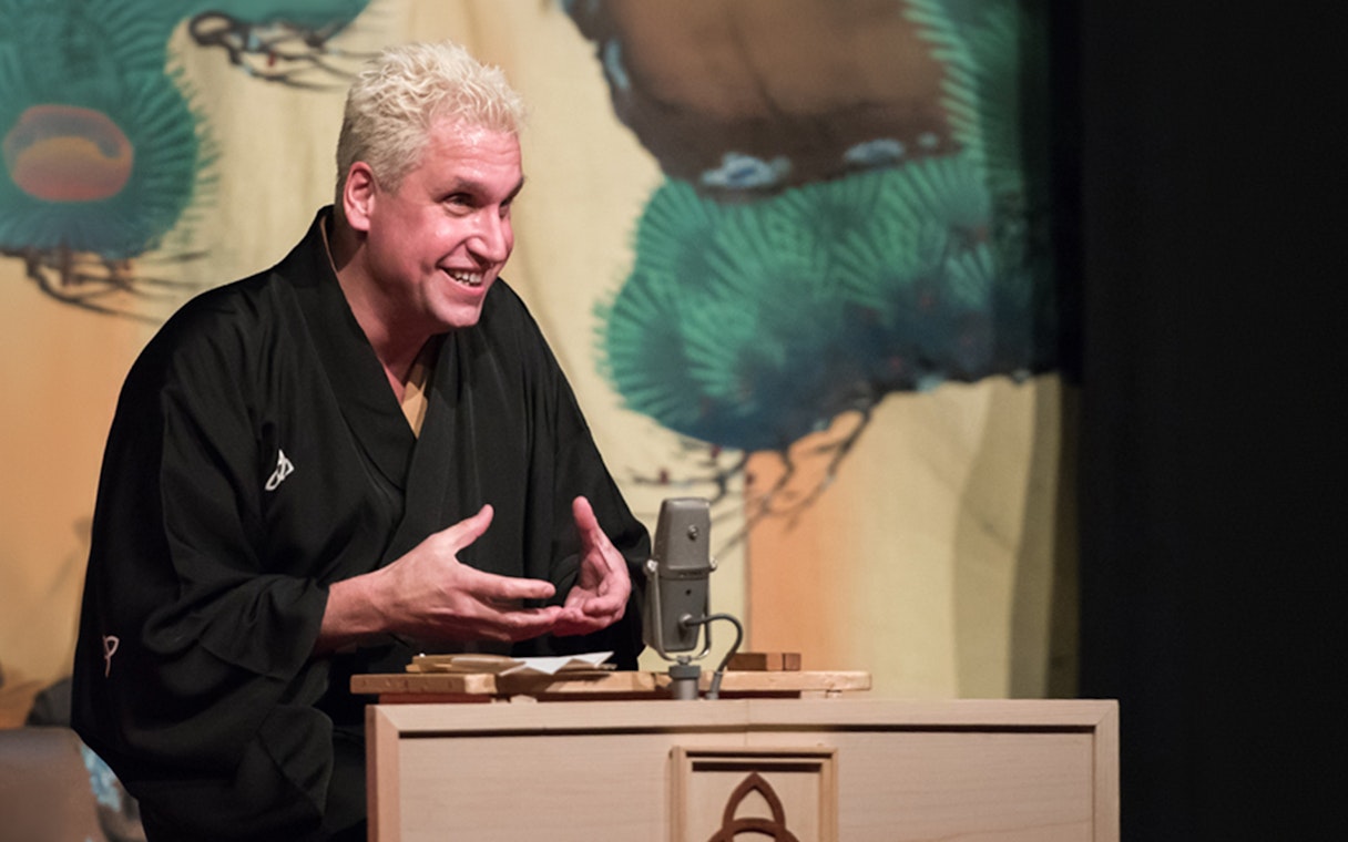 Performer in traditional attire delivering Rakugo storytelling on stage.
