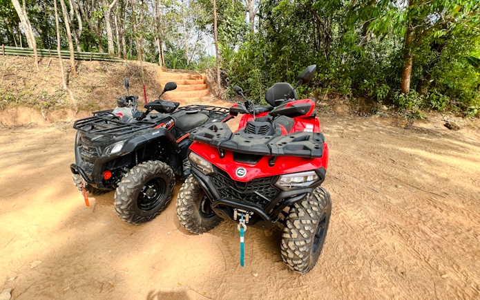 ATVs parked on a dirt path in a forest setting.