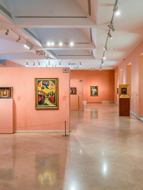 Thyssen Bornemisza Museum gallery with diverse paintings on pink walls.