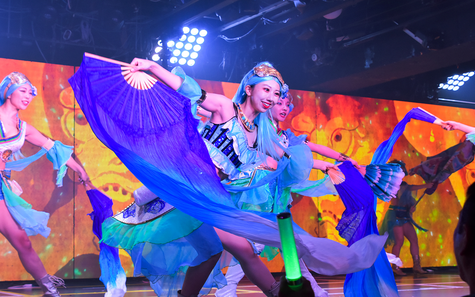 Performers in vibrant costumes dancing with fans at Samurai Restaurant show.