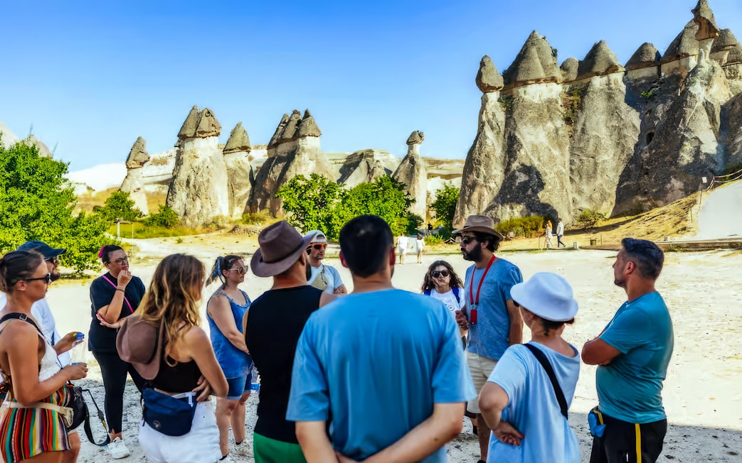Tourists with a guide in front of fairy chimneys in Göreme, Cappadocia.