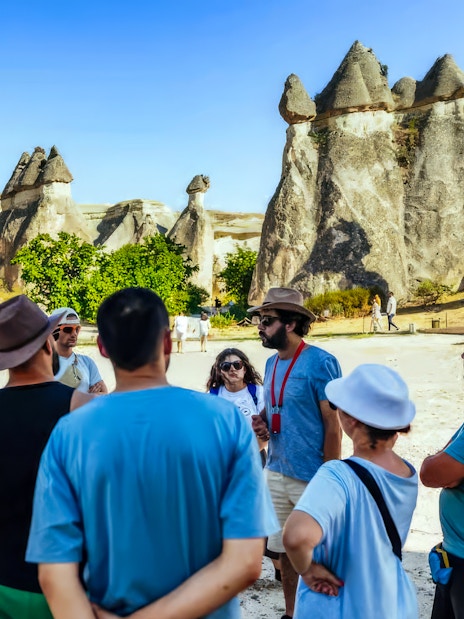 Tourists with a guide in front of fairy chimneys in Göreme, Cappadocia.