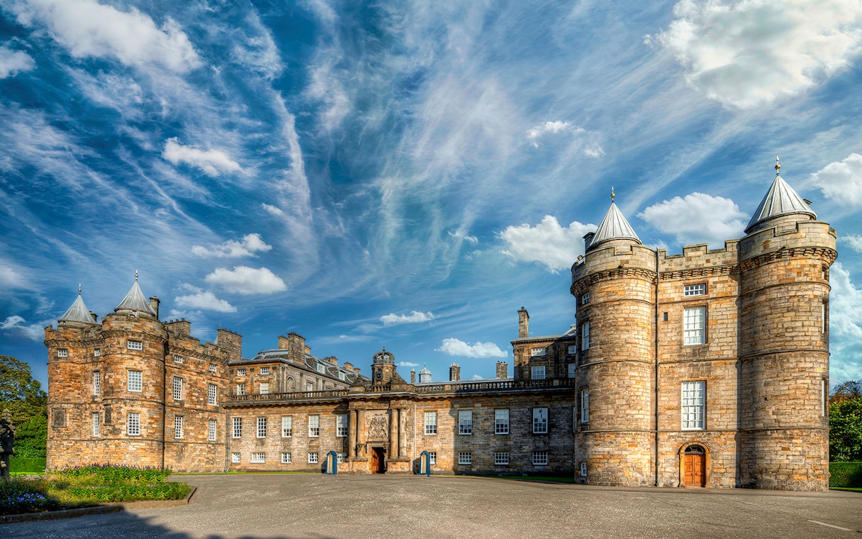 Palace of Holyroodhouse in Edinburgh with blue sky and clouds.