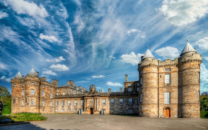 Palace of Holyroodhouse in Edinburgh with blue sky and clouds.