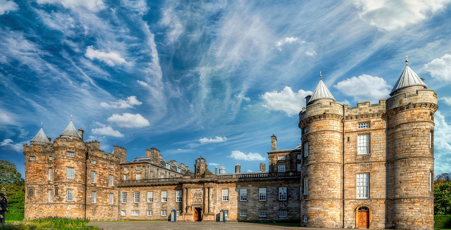 Palace of Holyroodhouse in Edinburgh with blue sky and clouds.