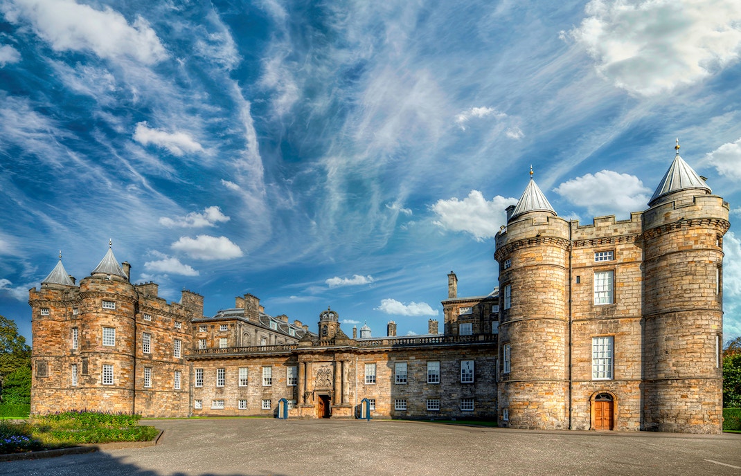 Palace of Holyroodhouse in Edinburgh with historic architecture and lush gardens.