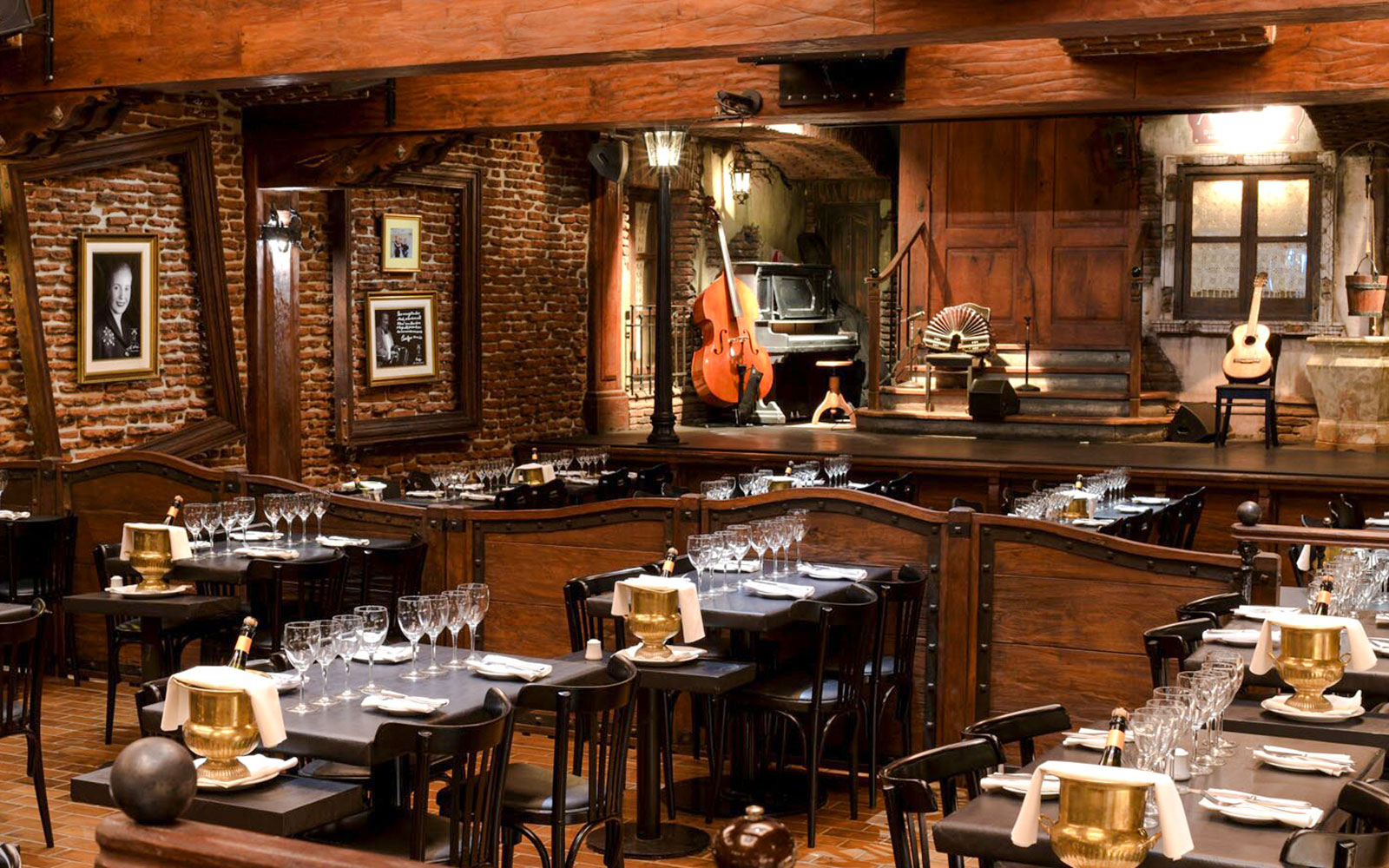 Dining area set for guests at Aljibe Tango Show with stage and musical instruments.