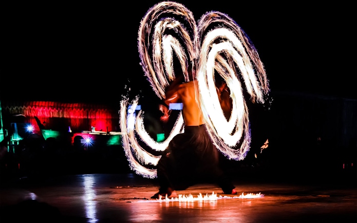 Fire dancer performing at night during Dubai desert safari tour.