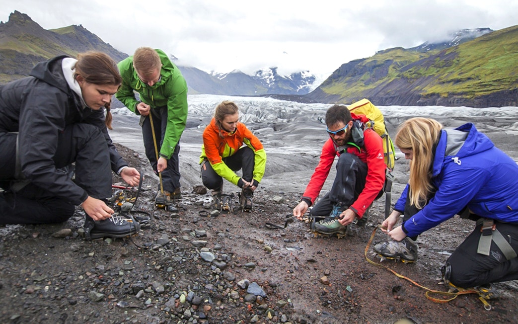 Tour guide assisting guests with crampons during Blue Ice Experience Glacier Hike at Skaftafell.