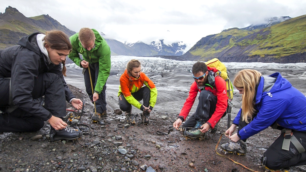 Tour guide assisting guests with crampons during Blue Ice Experience Glacier Hike at Skaftafell.
