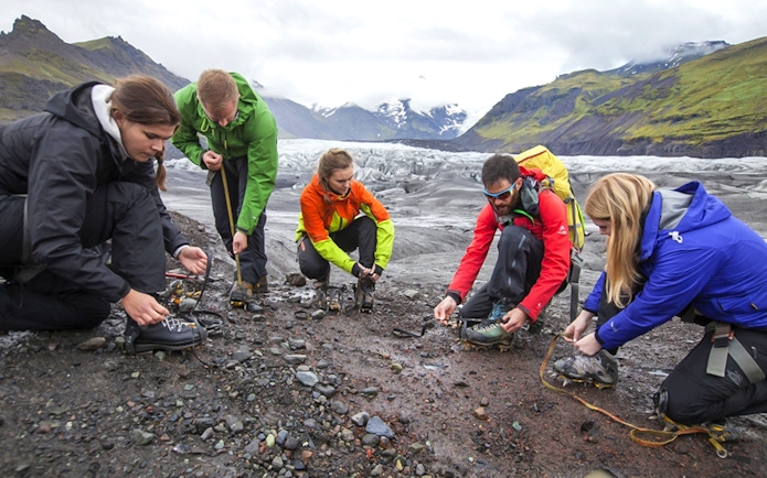 Tour guide assisting guests with crampons during Blue Ice Experience Glacier Hike at Skaftafell.