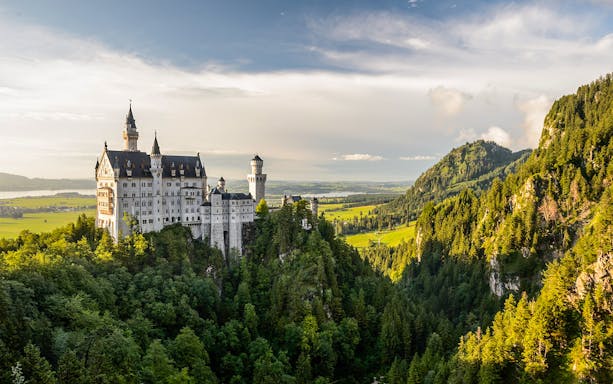 Neuschwanstein Castle exterior surrounded by lush green forest in Bavaria, Germany.