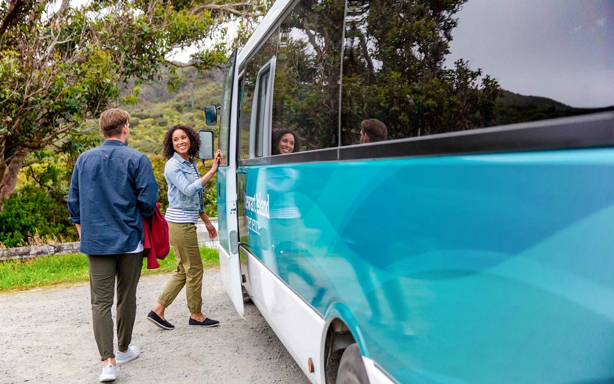 Tourists boarding a bus for the Stewart Island Village and Bays Tour.