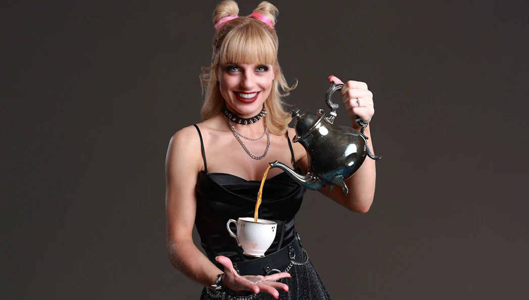 Performer pouring tea from a teapot into a cup at Late Night MAGIC show.