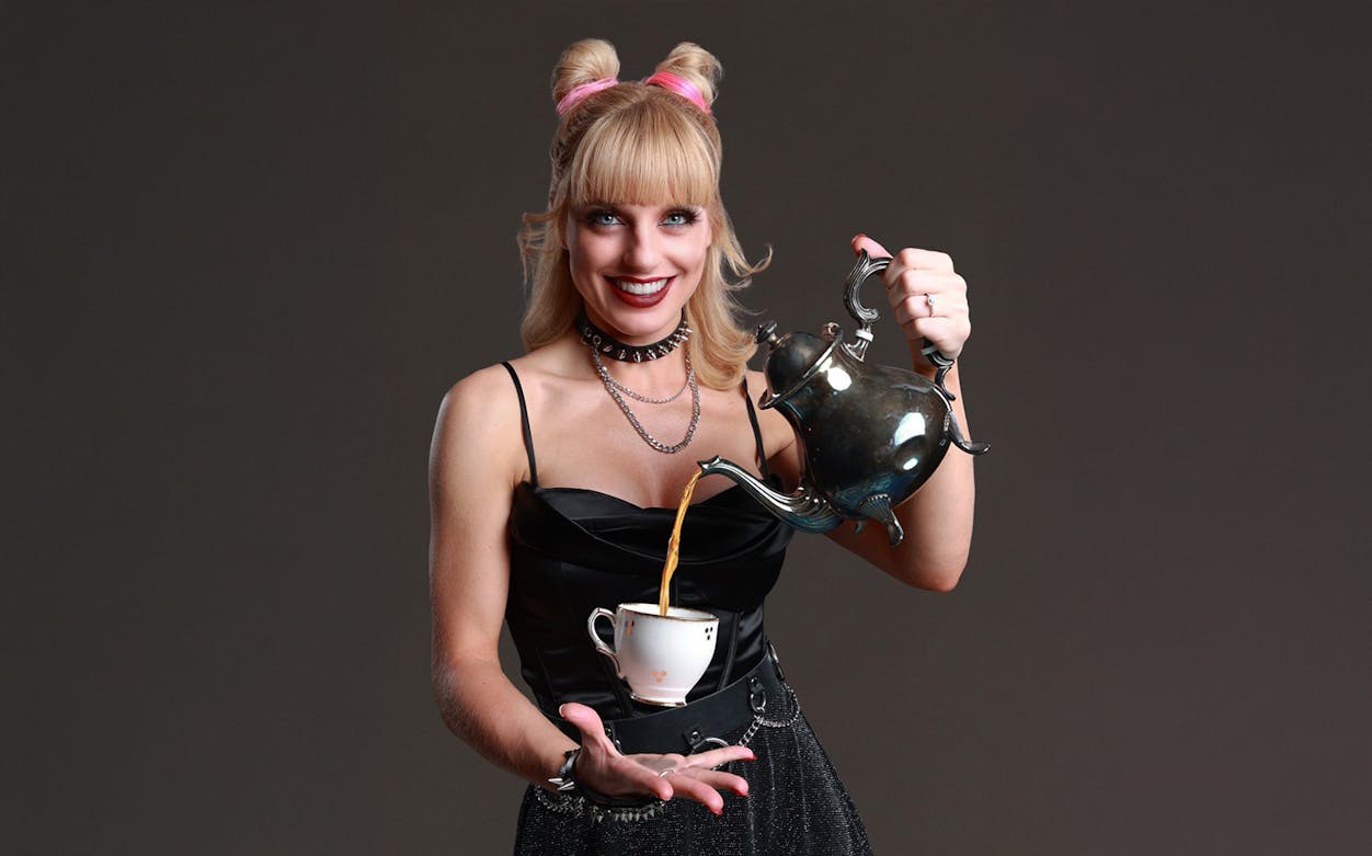 Performer pouring tea from a teapot into a cup at Late Night MAGIC show.