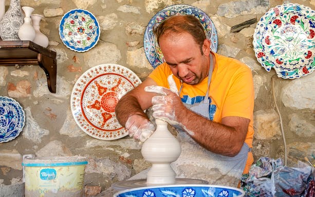 Pottery artist shaping clay on a wheel during Cappadocia Authentic Pottery Workshop Experience.