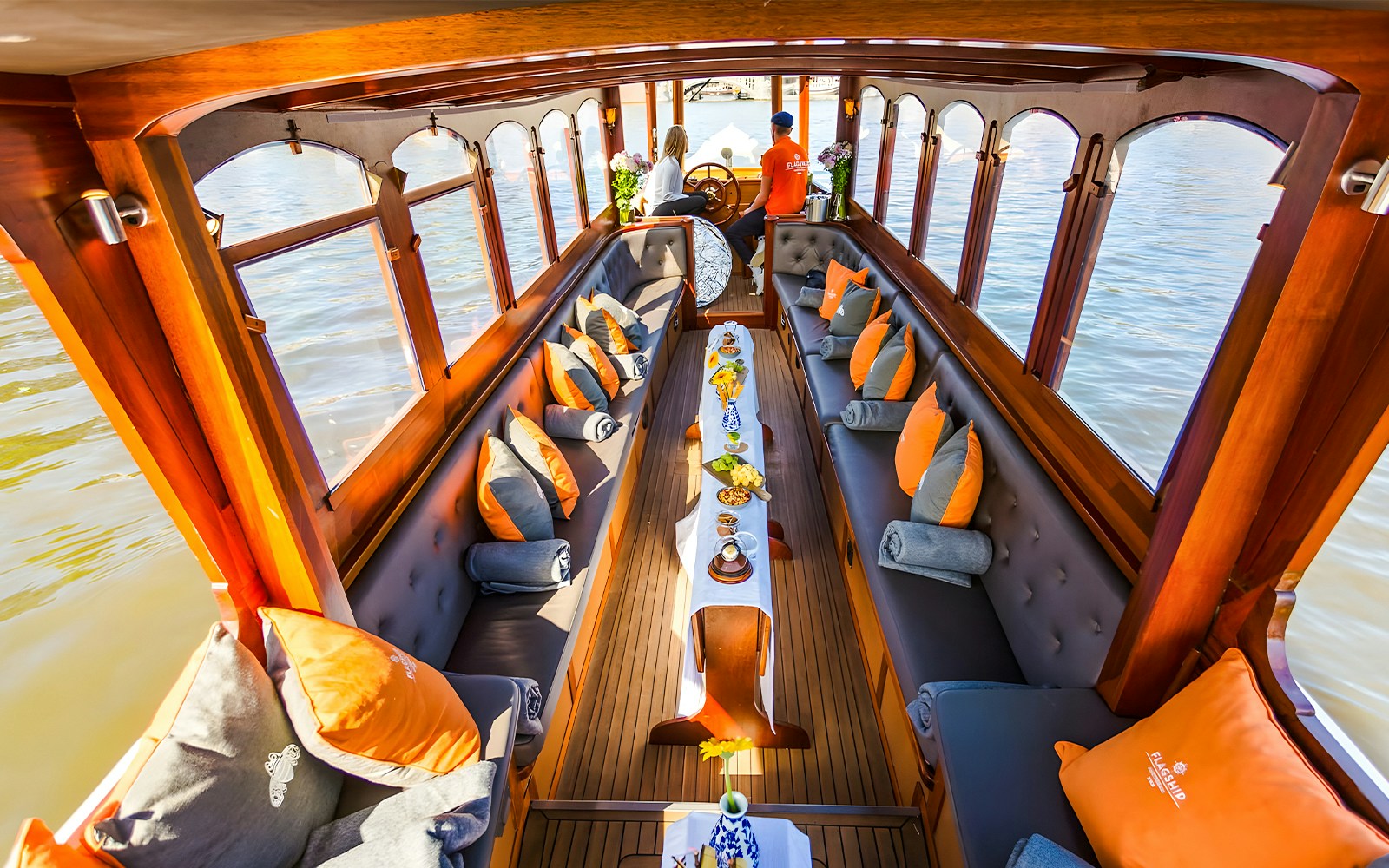 Saloon boat interior with seating and table setup, Amsterdam canal view.