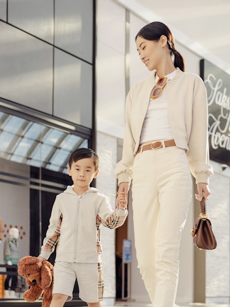 Parent and child holding hands while shopping at a mall.