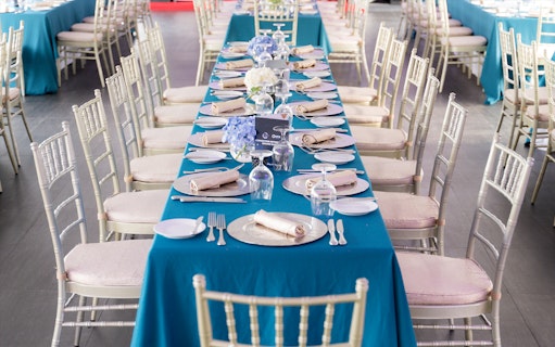 Elegant dining setup on Meridian Dinner Cruise with blue tablecloths and floral centerpieces.