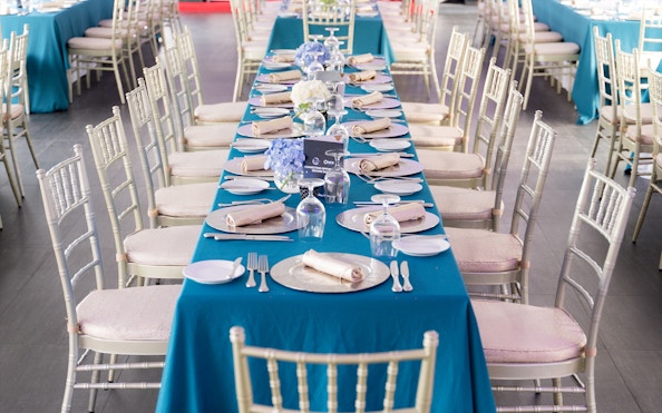 Elegant dining setup on Meridian Dinner Cruise with blue tablecloths and floral centerpieces.