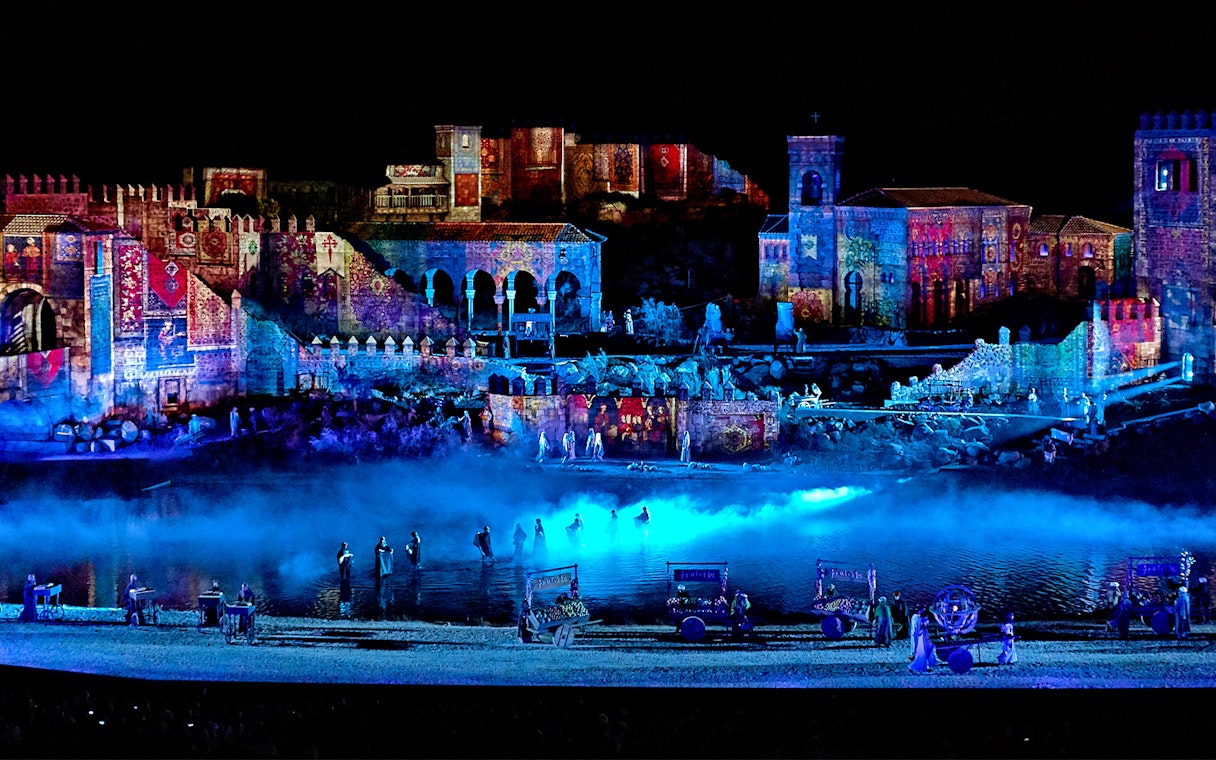 The Dream of Toledo Night Show with illuminated historic buildings and performers by a river.