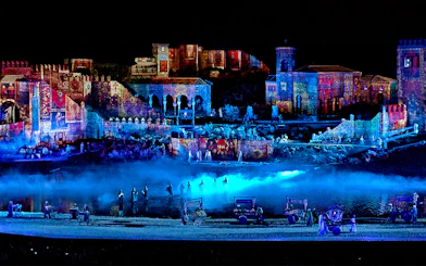 The Dream of Toledo Night Show with illuminated historic buildings and performers by a river.