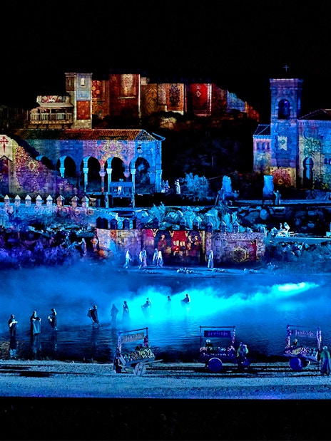 The Dream of Toledo Night Show with illuminated historic buildings and performers by a river.