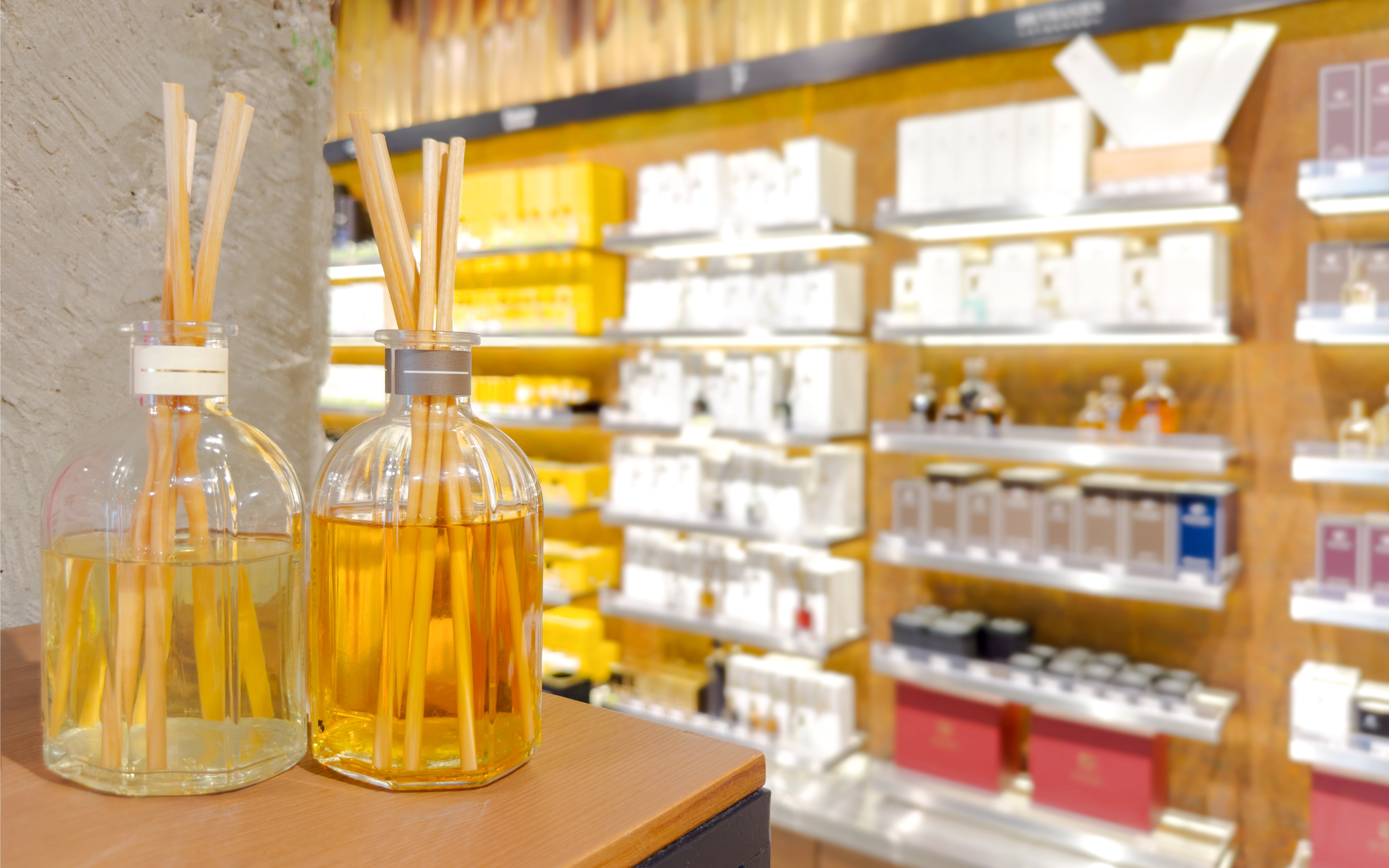 Reed diffusers on display in a perfume shop with shelves of fragrances in the background.