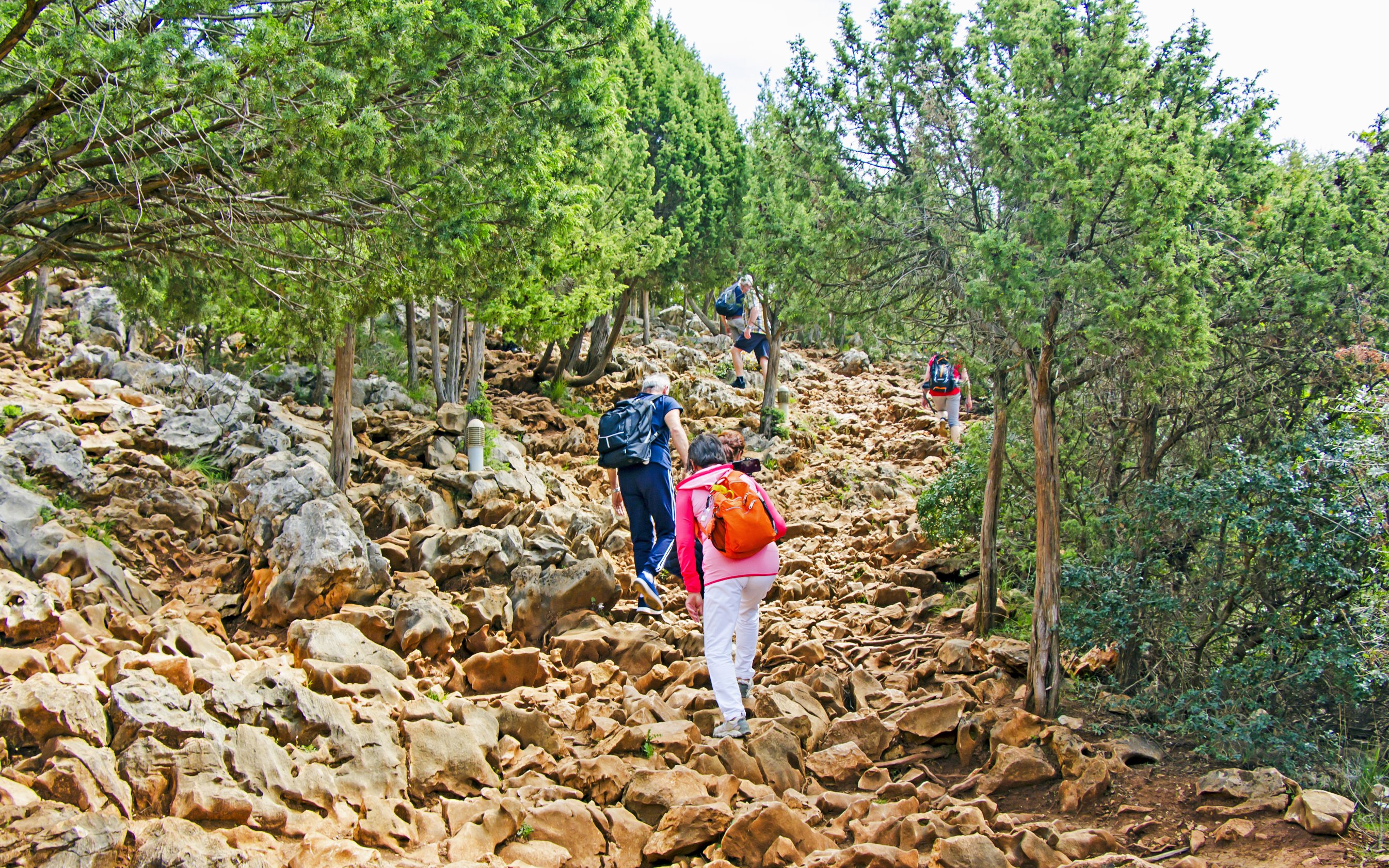 Hikers ascending rocky path on Apparition Hill, Podbrdo, Medjugorje, Bosnia and Herzegovina.