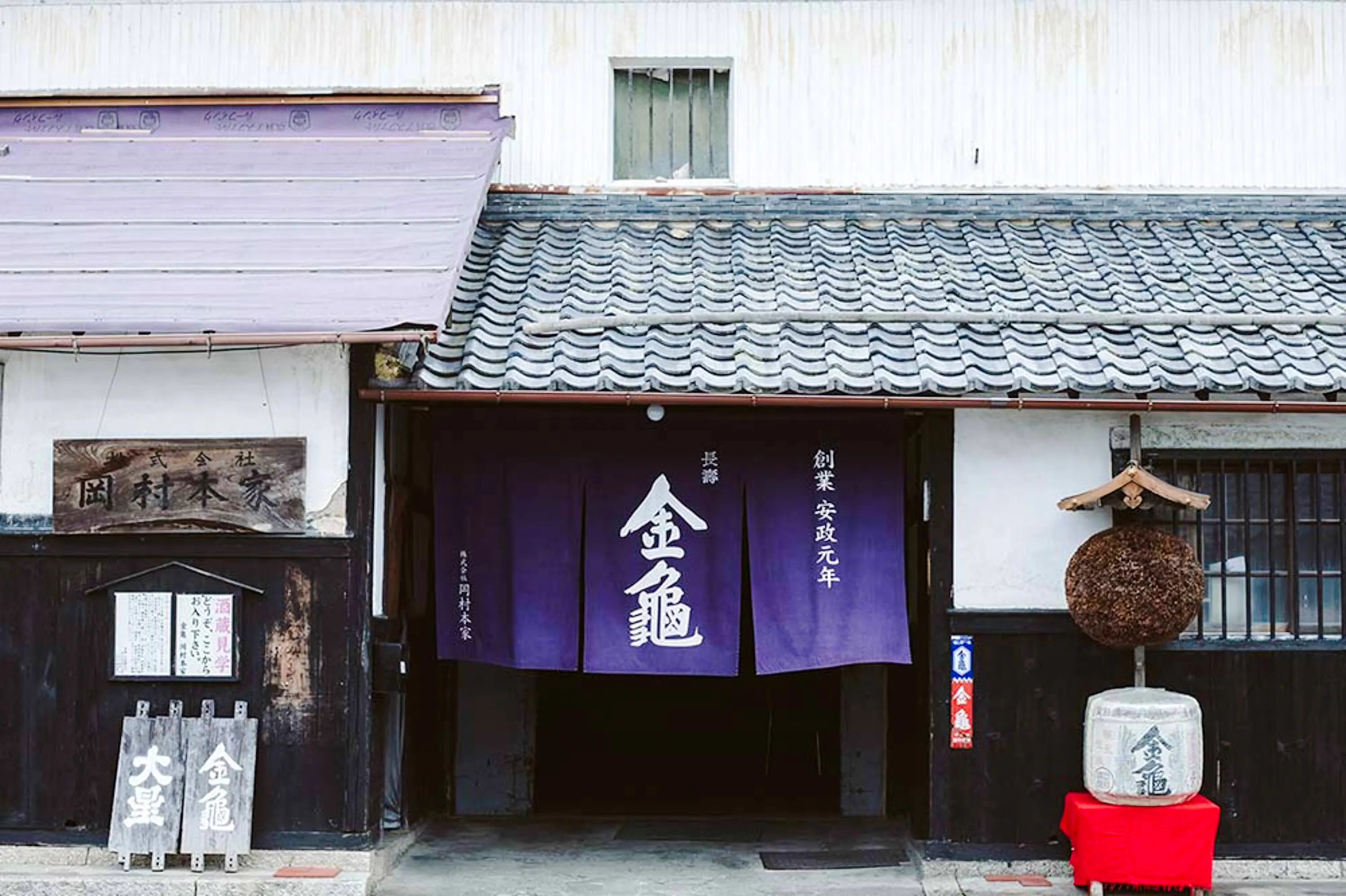 Entrance of Okamura Honke Sake Brewery in Shiga with traditional signage and decor.