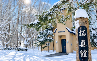 Snow-covered trees and building at Takushinkan in Hokkaido, Japan.