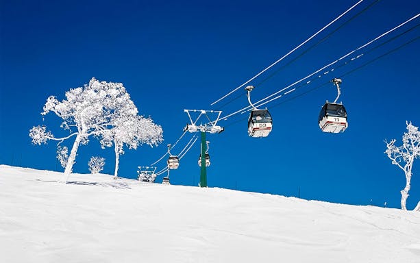 Ski gondolas over snowy slopes at Niseko Resort, Japan.