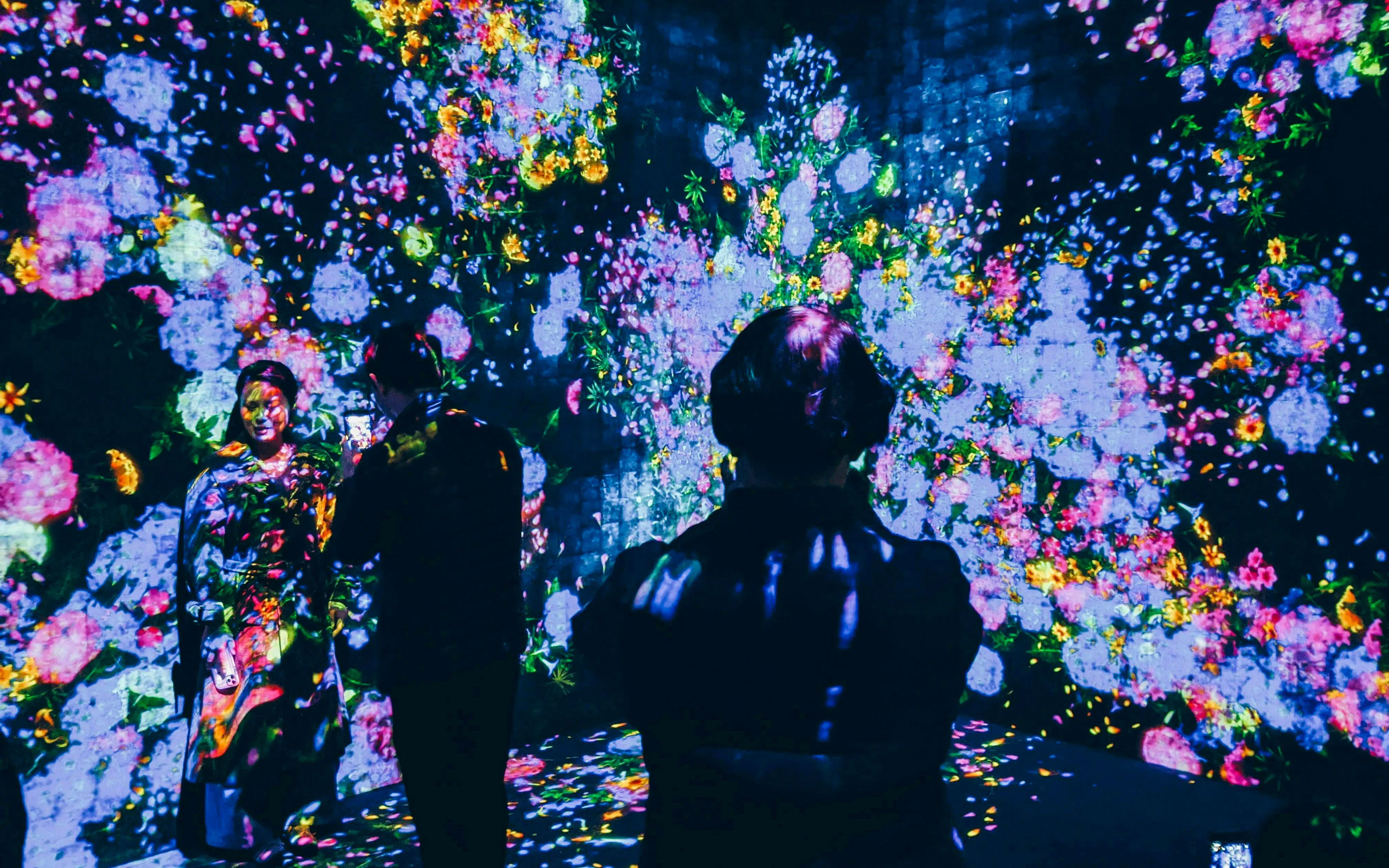 Visitors interacting with digital floral display at TeamLab Borderless Tokyo.