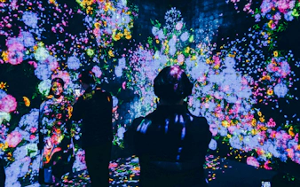 Visitors interacting with digital floral display at TeamLab Borderless Tokyo.