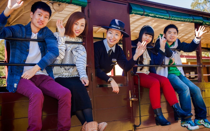 Conductor and passengers wave from a Puffing Billy carriage on a Melbourne tour.